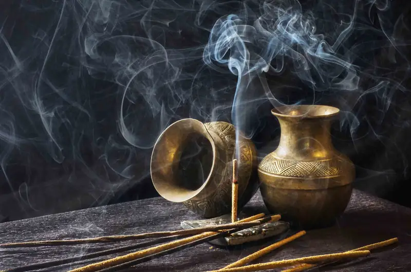 Incense smoke curling above brass vessels